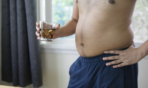 overweight man holding glass of aerated soft drink  bad for health